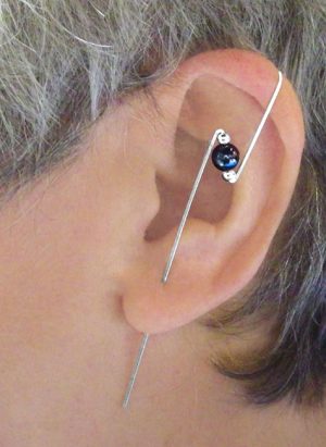 Ear of a model with a bolt design ear climber with a large single bead and two much smaller beads on each side. | Ear Curls, Ear Climbers