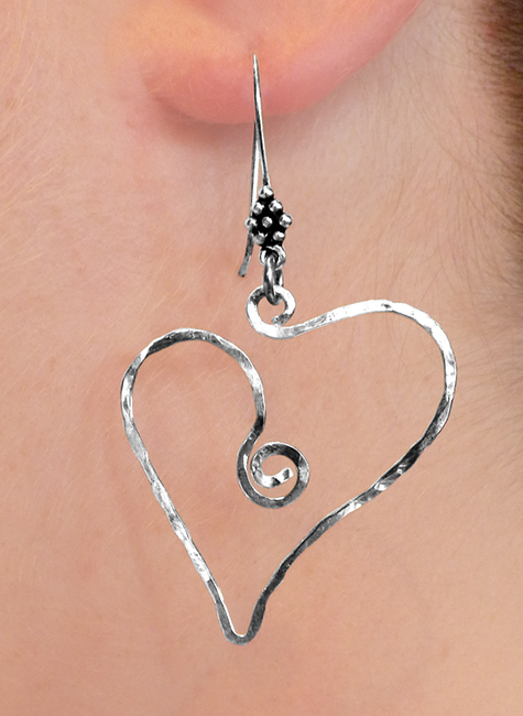 Single heart shaped earring hanging from a models ear. | Ear Curls, Ear Climbers